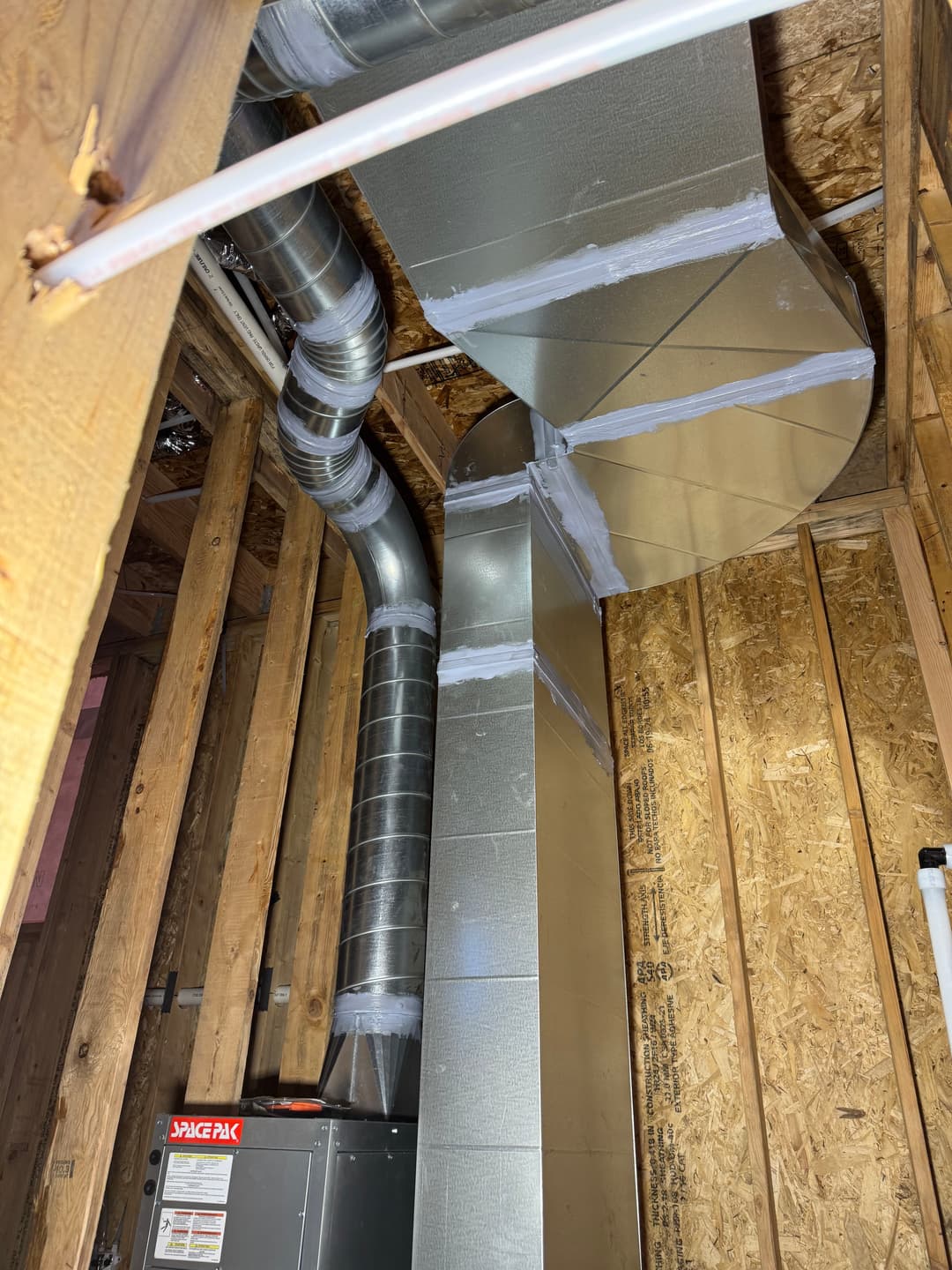 HVAC ductwork installation in a wooden frame, showing metal ducts and equipment.