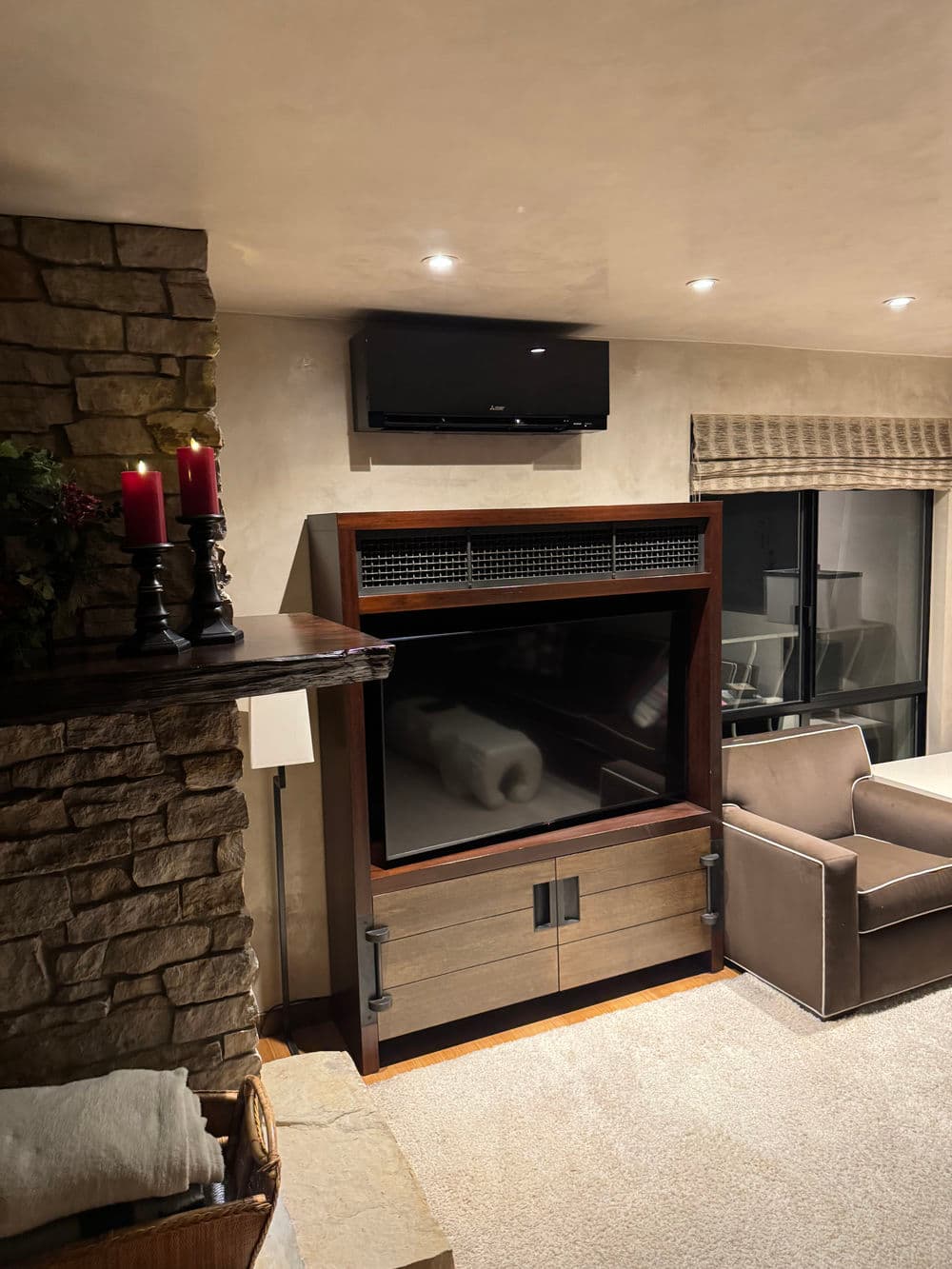 Modern living room with stone fireplace, stylish TV unit, and cozy seating. Warm ambiance.